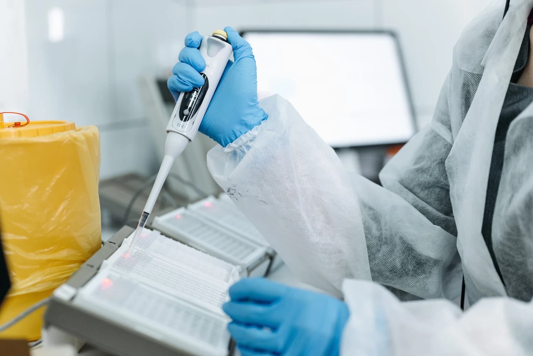 Mavi eldivenli bir araştırmacının laboratuvar tezgâhında mikropipetle çalışması.