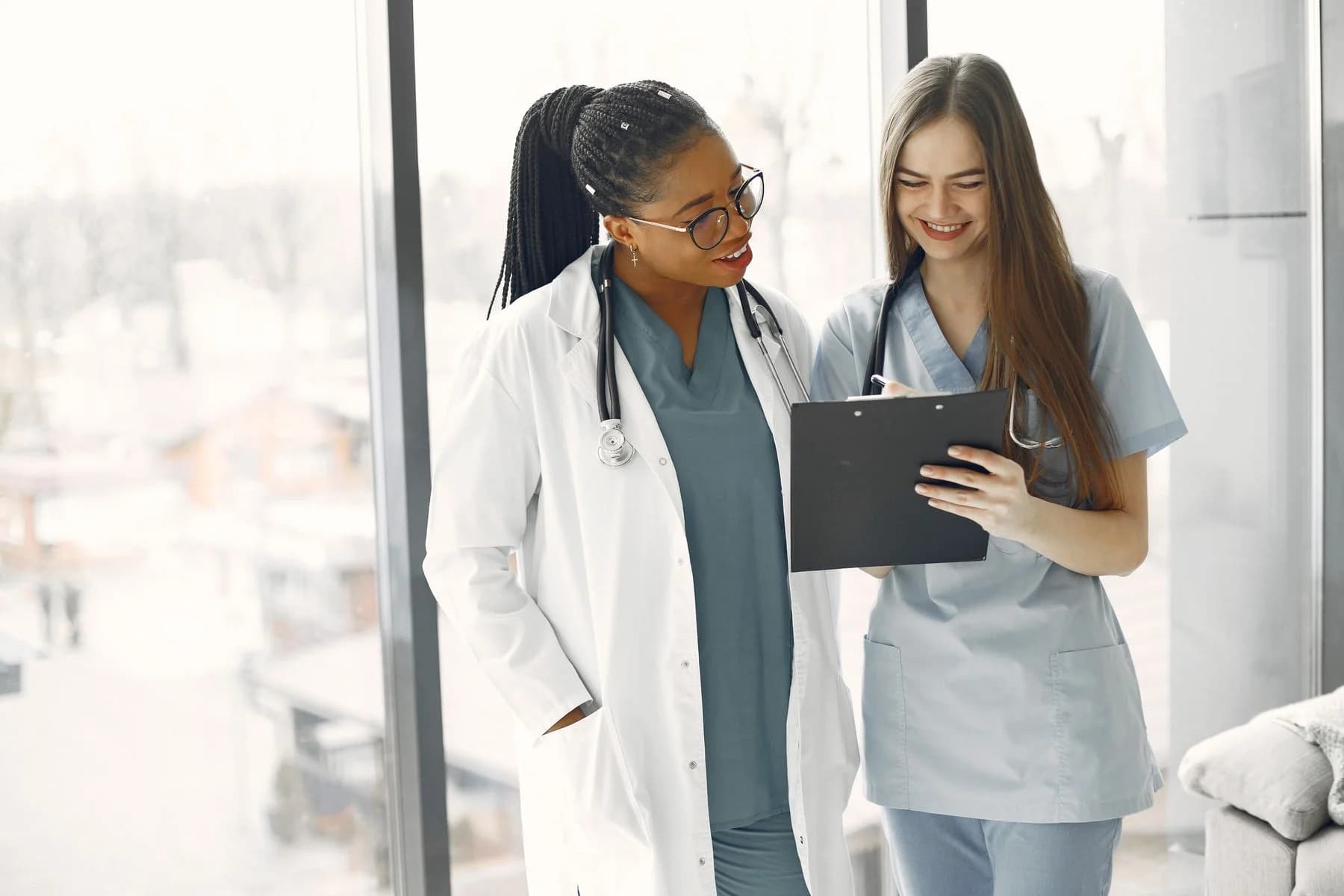 Aydınlık bir klinik ortamında iki sağlık profesyonelinin bir belgeyi birlikte incelemesi.